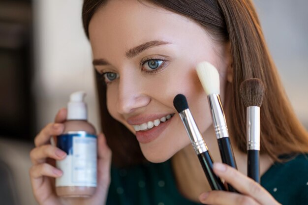 mujer joven, tenencia, cara, cepillos, y, sonriente