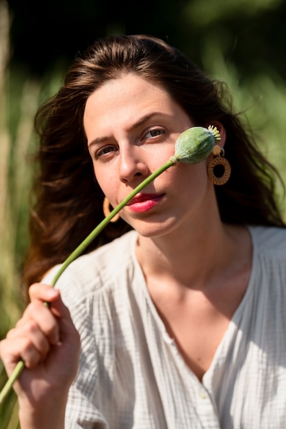 mujer joven, tenencia, flor, vista delantera