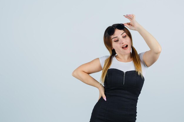 Mujer joven, tenencia, mano, en, anteojos, mientras, mirar hacia abajo