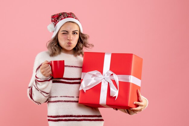 mujer joven, tenencia, navidad, presente, y, taza de té, en, rosa