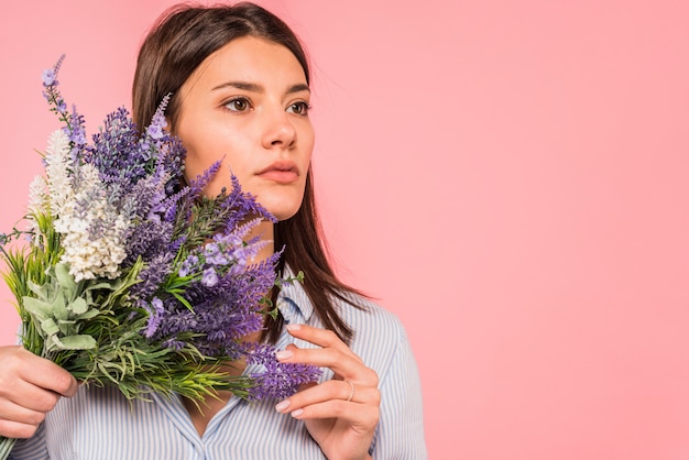 Mujer joven, tenencia, ramo de flores, cerca de la cara