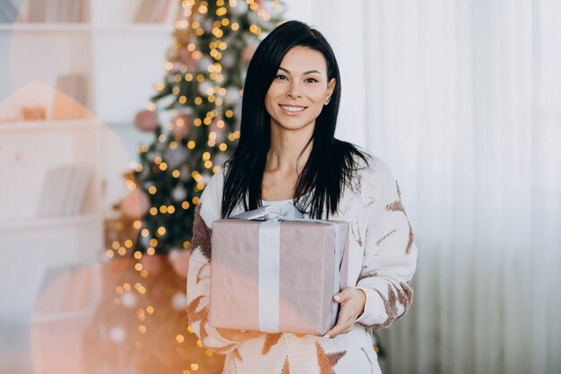 Mujer joven, tenencia, regalo de navidad, por, árbol de navidad