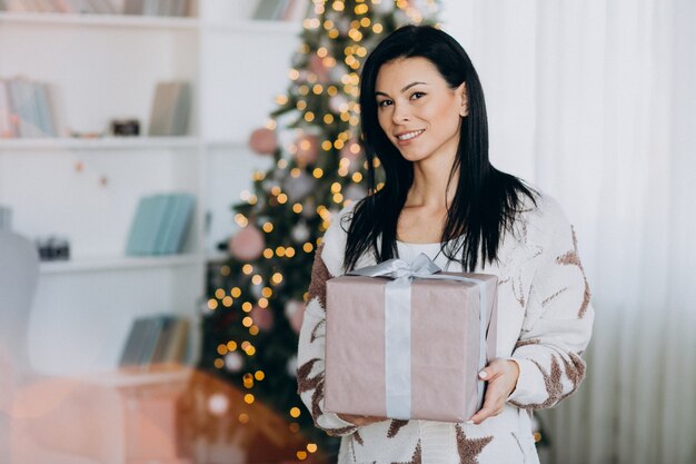 Mujer joven, tenencia, regalo de navidad, por, árbol de navidad