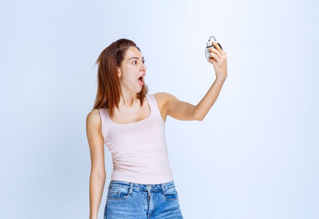 Mujer joven, tenencia, un, reloj, y, control del tiempo