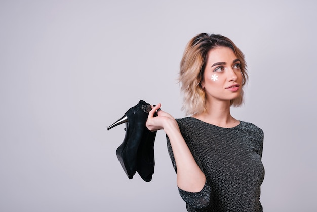 Mujer joven, tenencia, zapatos, después, fiesta