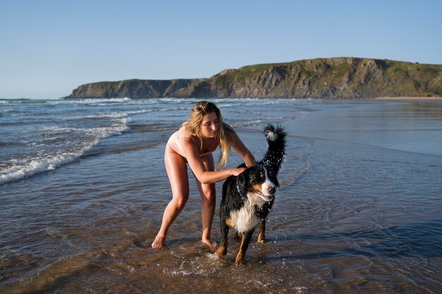 mujer joven, tener diversión, con, perro, en la playa
