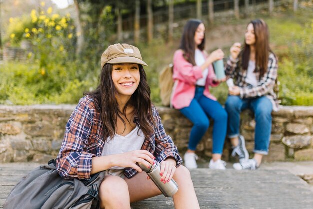 Mujer joven con termo cerca de amigos