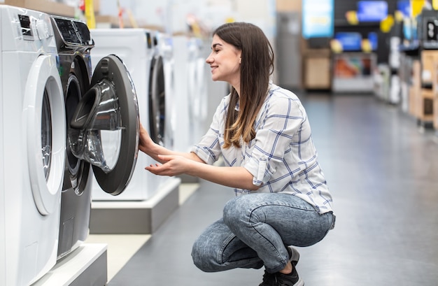 Una mujer joven en una tienda elige una lavadora.
