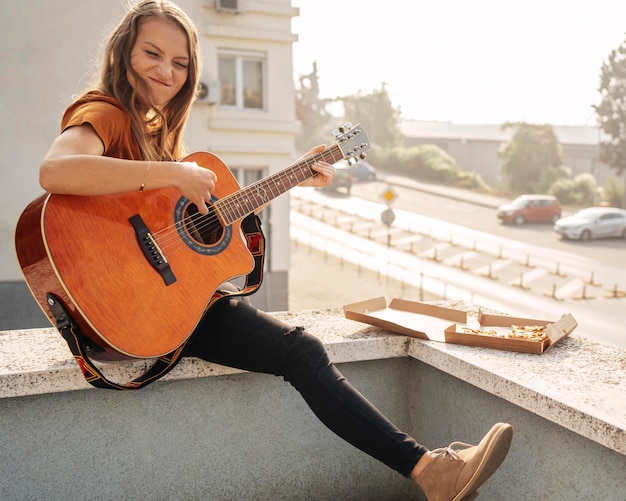 Mujer joven de tiro largo tocando la guitarra