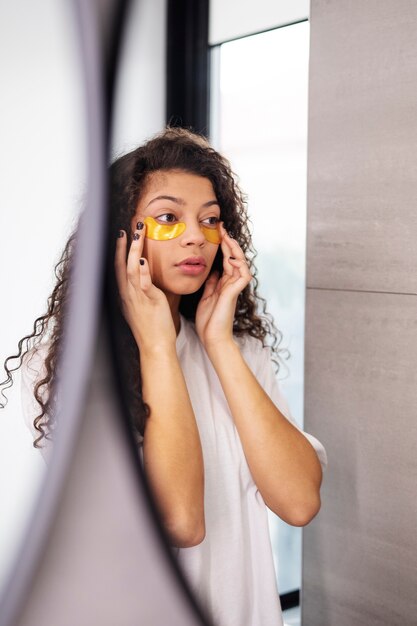 Foto gratuita mujer joven de tiro medio aplicando parche en el ojo