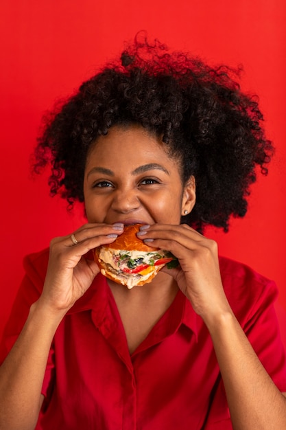 Mujer joven de tiro medio comiendo hamburguesa