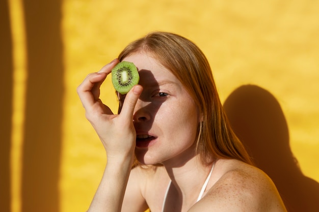 Mujer joven de tiro medio posando con kiwi