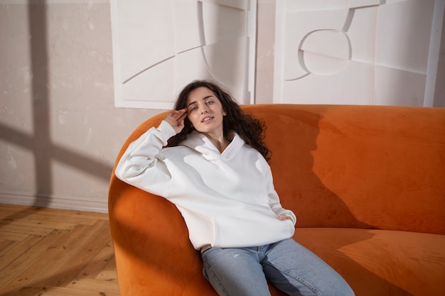 Foto gratuita mujer joven de tiro medio sentada en el sofá