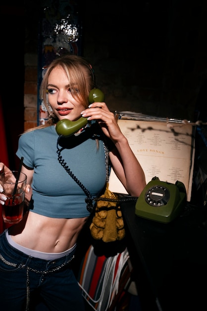 Mujer joven de tiro medio con teléfono vintage