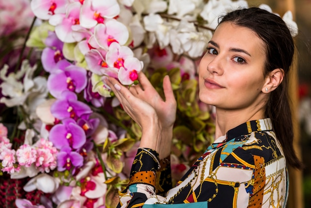 Foto gratuita mujer joven tocando flores en casa verde