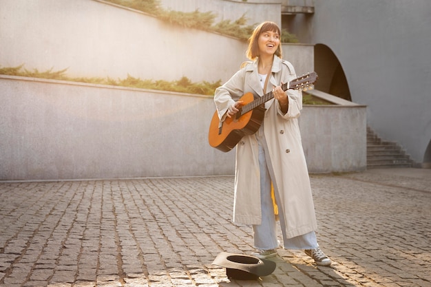 Foto gratuita mujer joven tocando la guitarra al aire libre con espacio de copia