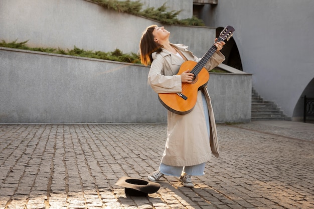 Mujer joven tocando la guitarra al aire libre con espacio de copia