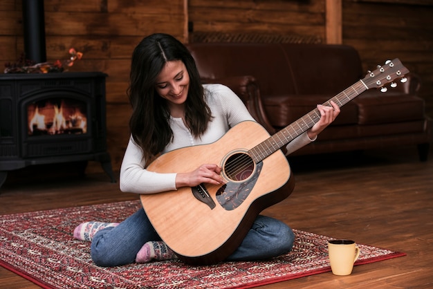 Foto gratuita mujer joven tocando la guitarra en casa