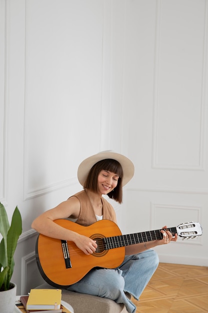 Mujer joven tocando la guitarra en interiores con espacio de copia