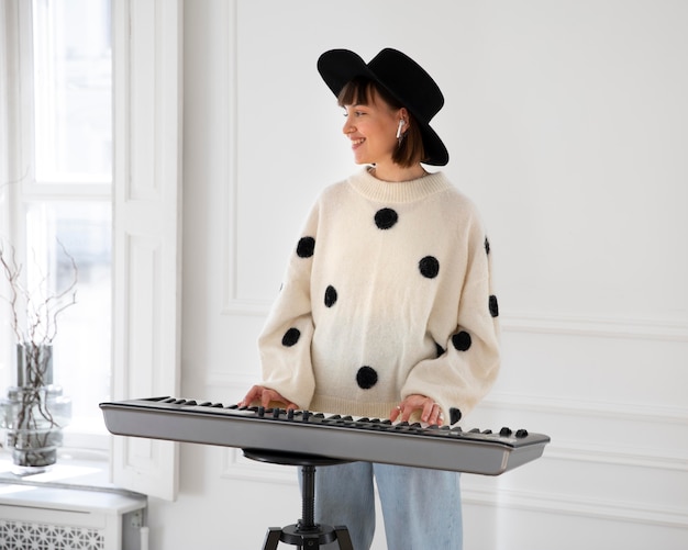 Foto gratuita mujer joven tocando el piano en el interior