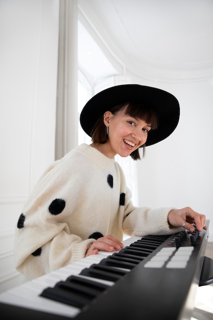 Foto gratuita mujer joven tocando el piano en el interior