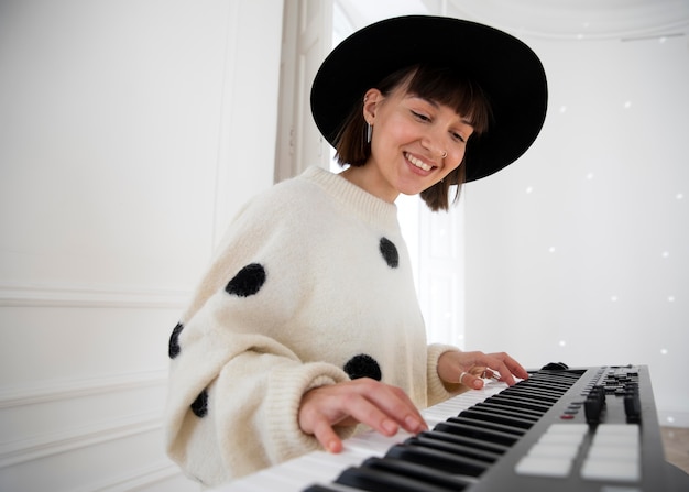 Foto gratuita mujer joven tocando el piano en el interior