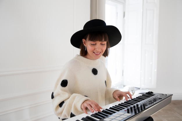 Foto gratuita mujer joven tocando el piano en el interior