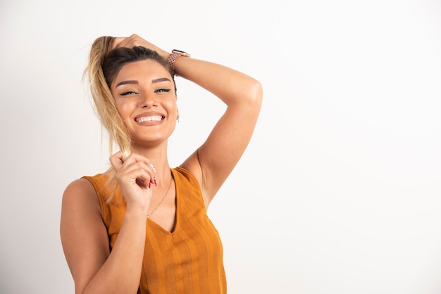 Foto gratuita mujer joven tocando su cabello y posando sobre fondo blanco.