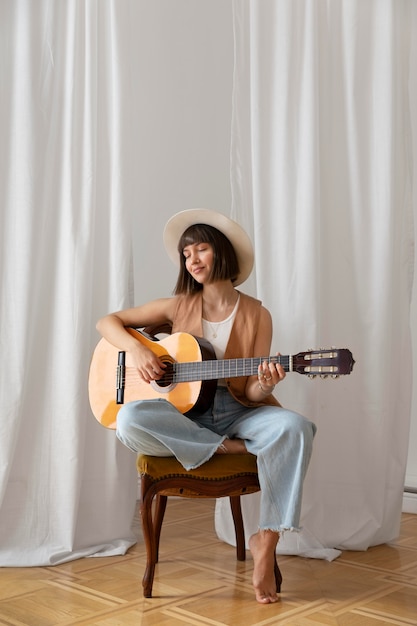 Mujer joven, tocar la guitarra, adentro