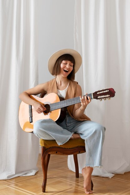 Mujer joven, tocar la guitarra, adentro