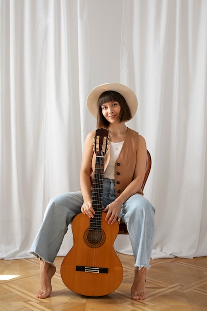 Foto gratuita mujer joven, tocar la guitarra, adentro