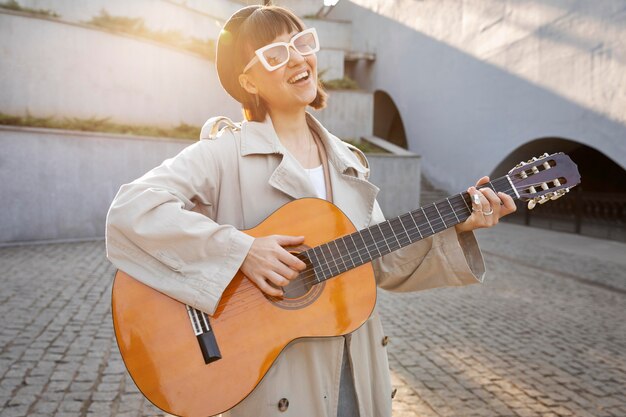 Mujer joven, tocar la guitarra, aire libre