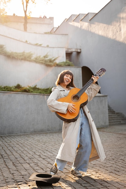 Foto gratuita mujer joven, tocar la guitarra, aire libre