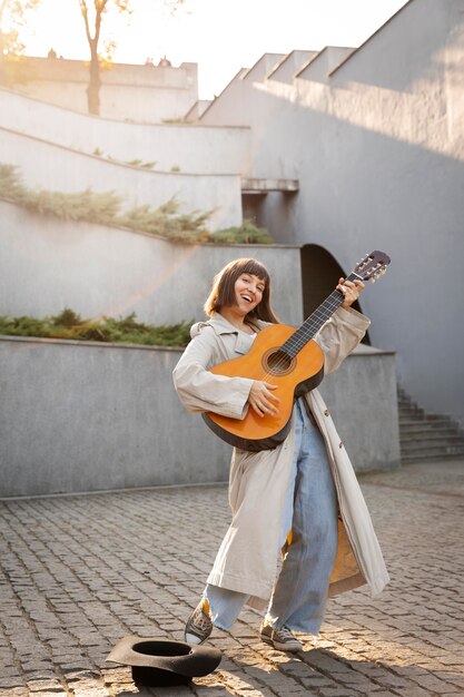 Mujer joven, tocar la guitarra, aire libre