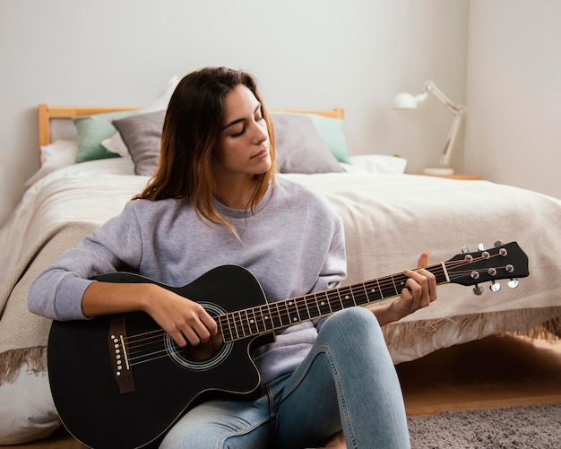 Mujer joven, tocar la guitarra, en casa