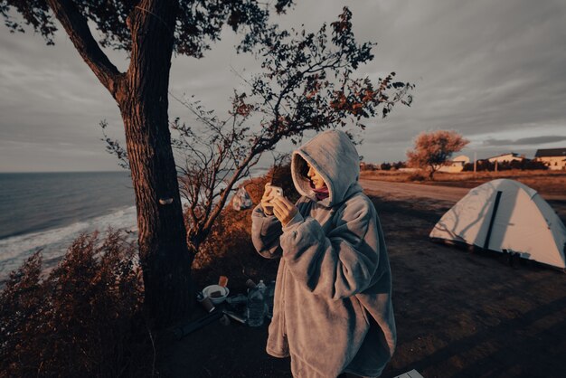 Mujer joven toma fotografías de la puesta de sol del mar por teléfono inteligente