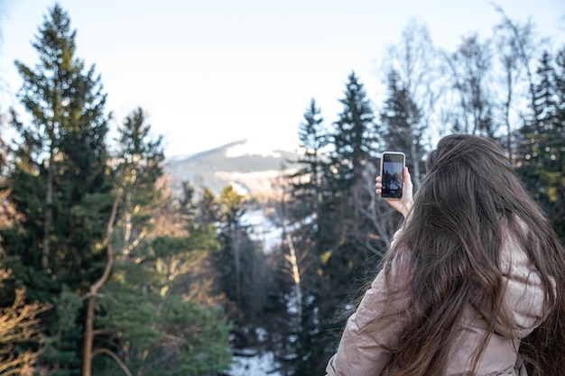 Una mujer joven toma fotos de las montañas en un teléfono inteligente