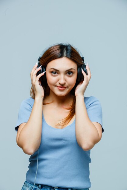 Mujer joven tomados de la mano en los auriculares mientras escucha música