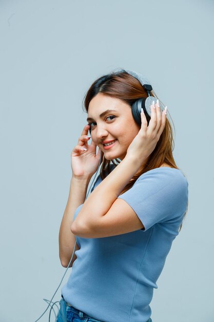 Mujer joven tomados de la mano en los auriculares mientras escucha música