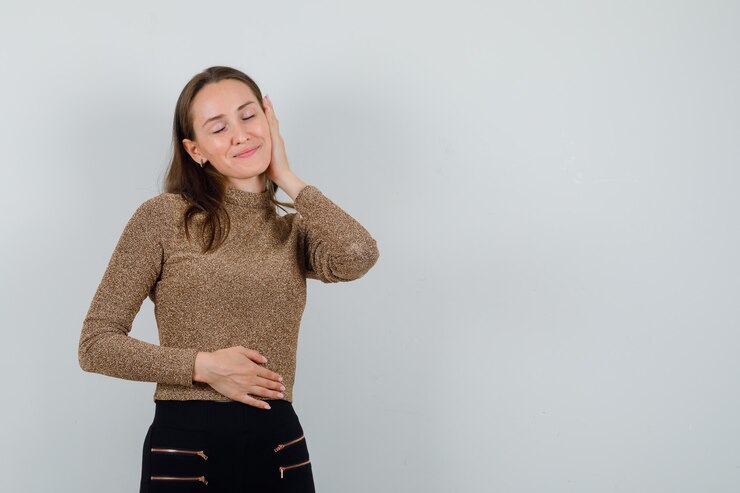 Foto gratuito mujer joven tomados de la mano en la cara mientras cierra los ojos con una blusa dorada y se ve impresionante, vista frontal. espacio para texto