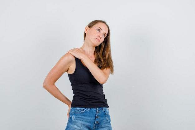 Foto gratuita mujer joven tomados de la mano en el hombro y la espalda en camiseta, pantalones cortos y mirando triste