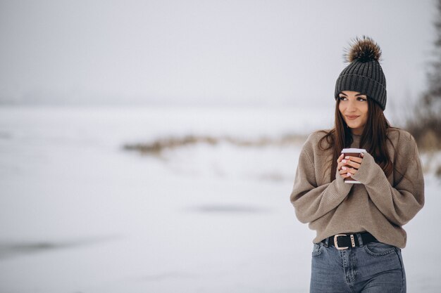 Mujer joven tomando café afuera en el parque de invierno