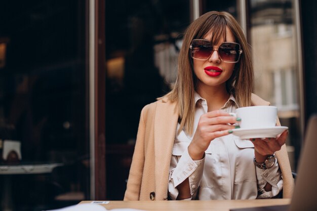 Mujer joven tomando café en un café en la terraza