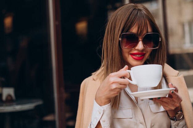 Mujer joven tomando café en un café en la terraza