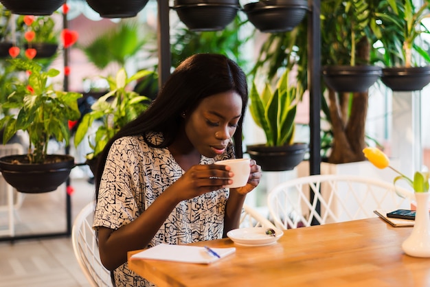 Mujer joven tomando café en la cafetería moderna