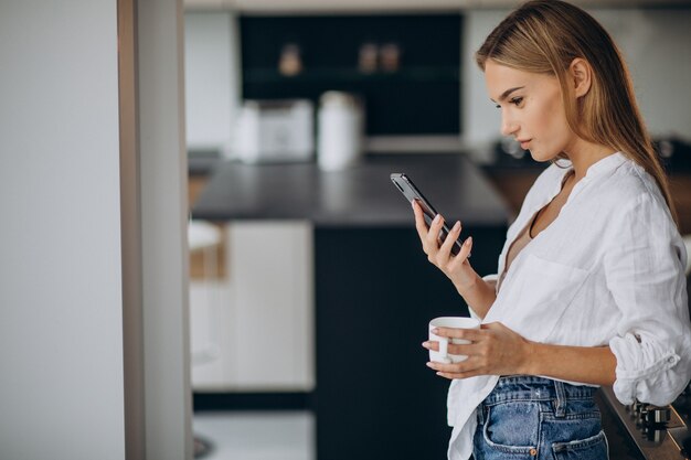 Mujer joven tomando café en la cocina