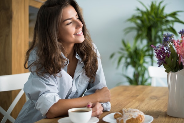 Mujer joven tomando café en el comedor