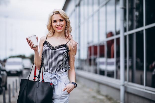 Mujer joven tomando café fuera de la calle