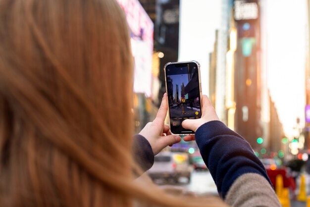 Mujer joven tomando una foto de la ciudad de nueva york durante el día