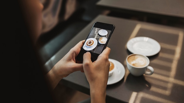 Foto gratuita mujer joven tomando una foto de su café